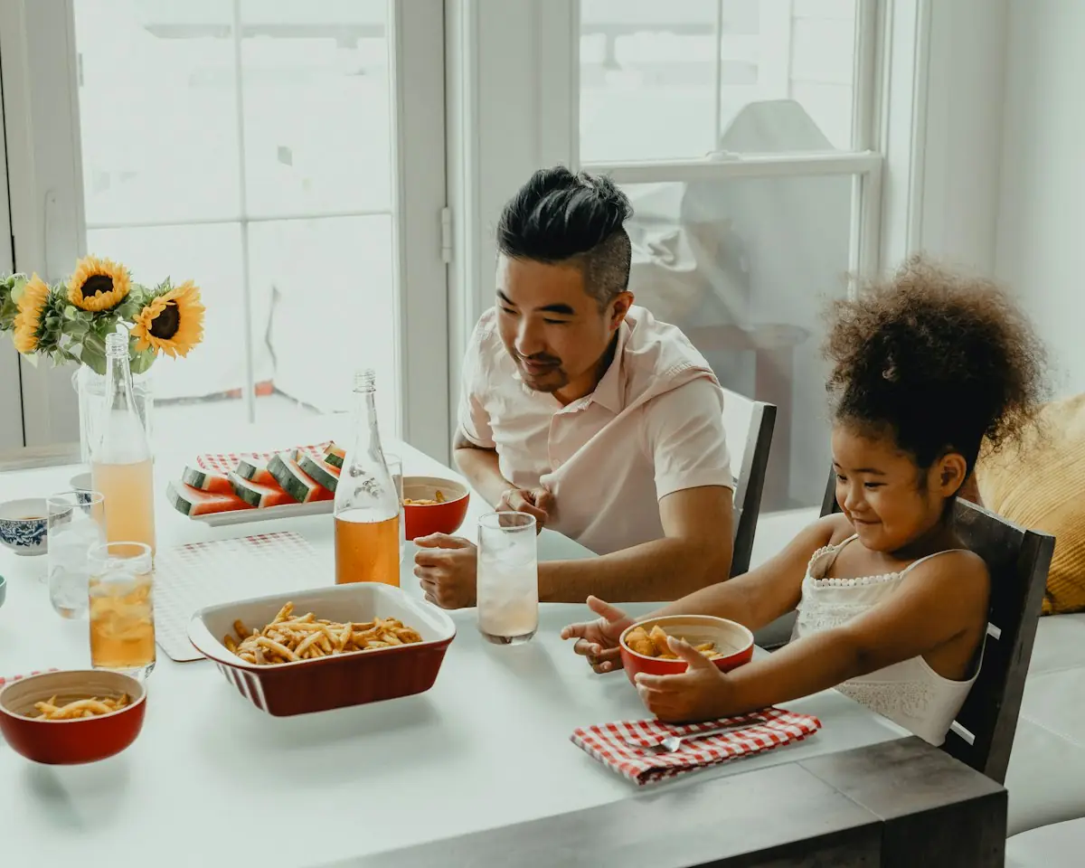 Un père et sa fille à table, devant un plat fait maison